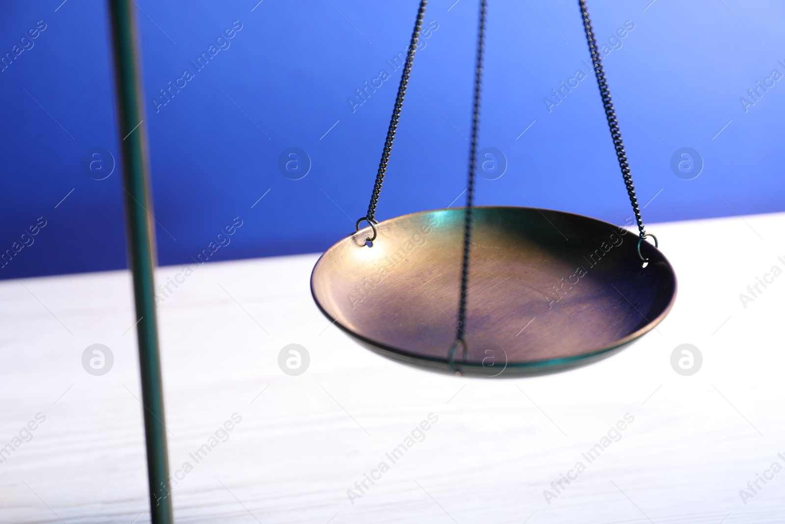 Photo of Scales of justice on table against light blue background, closeup