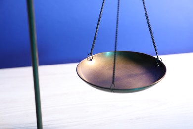 Photo of Scales of justice on table against light blue background, closeup