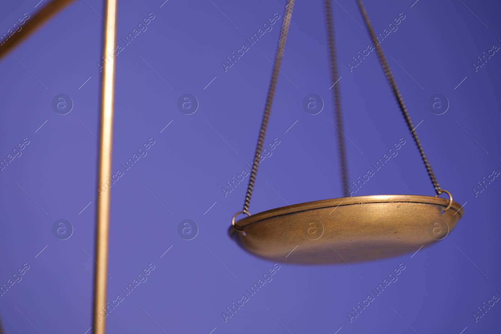 Photo of Scales of justice on violet background, closeup