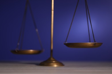 Photo of Scales of justice on wooden table against dark background, closeup