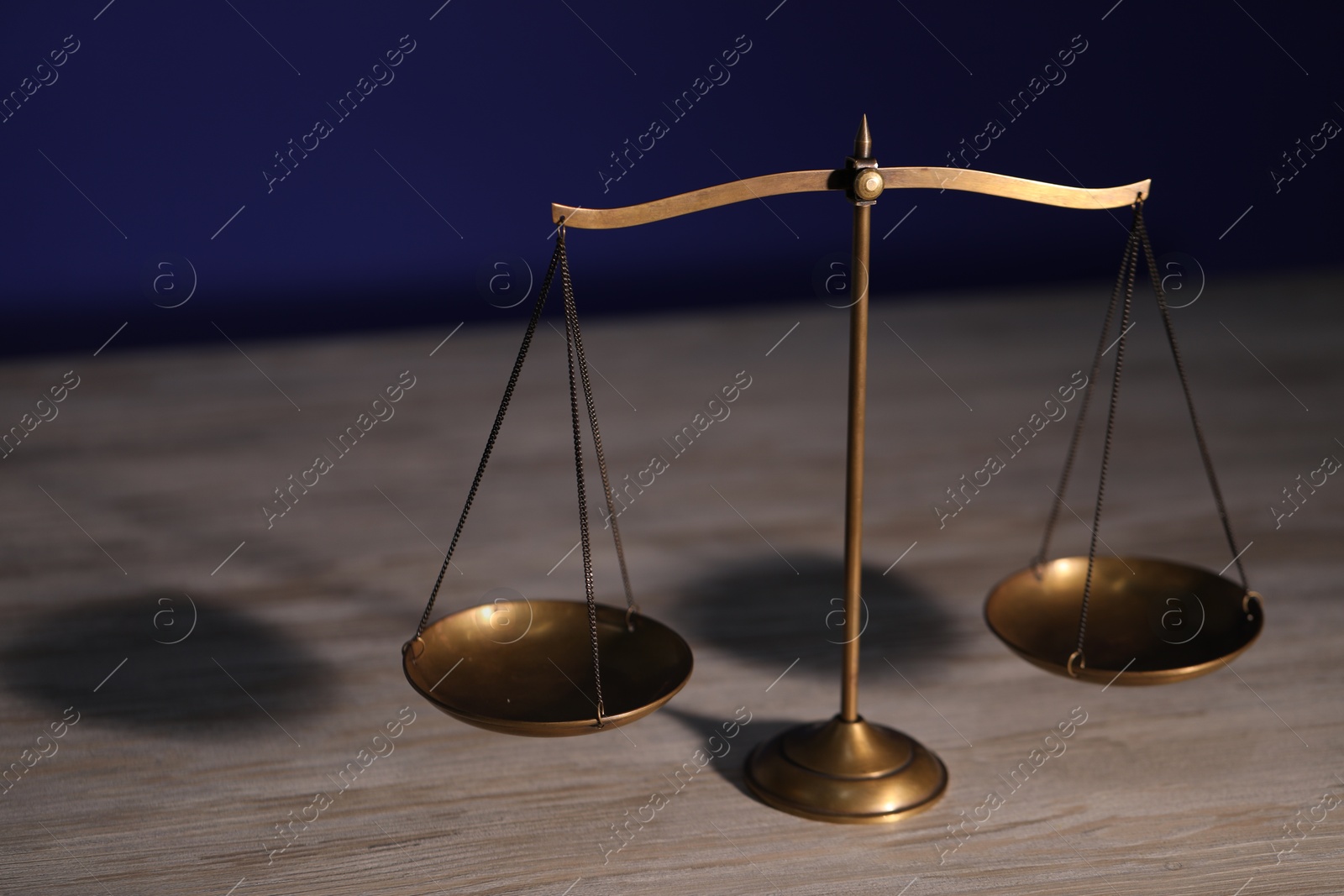 Photo of Scales of justice on wooden table against dark background