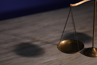 Photo of Scales of justice on wooden table, closeup. Space for text