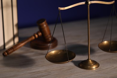 Photo of Scales of justice, books and judge's gavel on wooden table, closeup