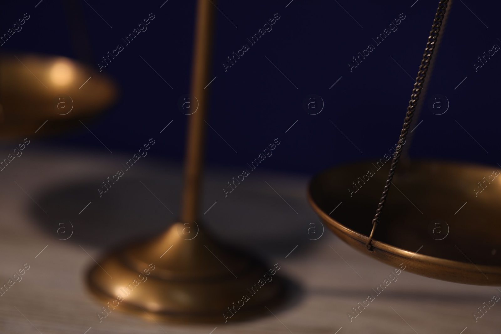 Photo of Scales of justice on table against dark background, closeup