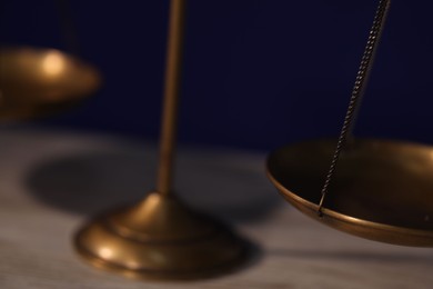 Photo of Scales of justice on table against dark background, closeup