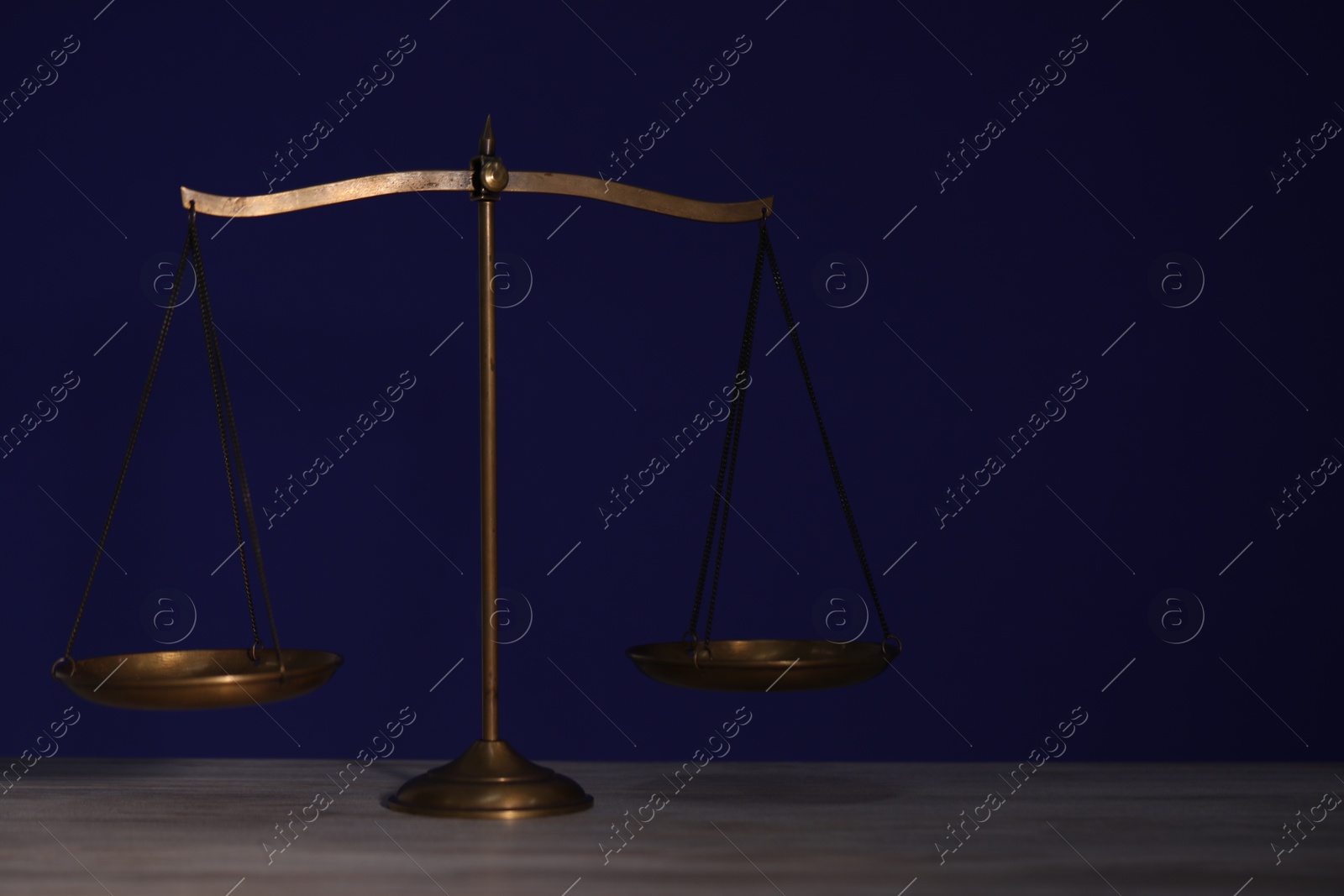 Photo of Scales of justice on wooden table against dark background
