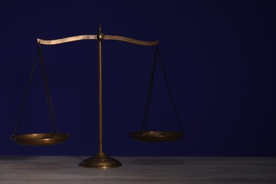 Photo of Scales of justice on wooden table against dark background