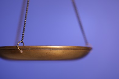Photo of Scales of justice on violet background, closeup