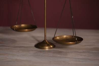 Photo of Scales of justice on wooden table, closeup