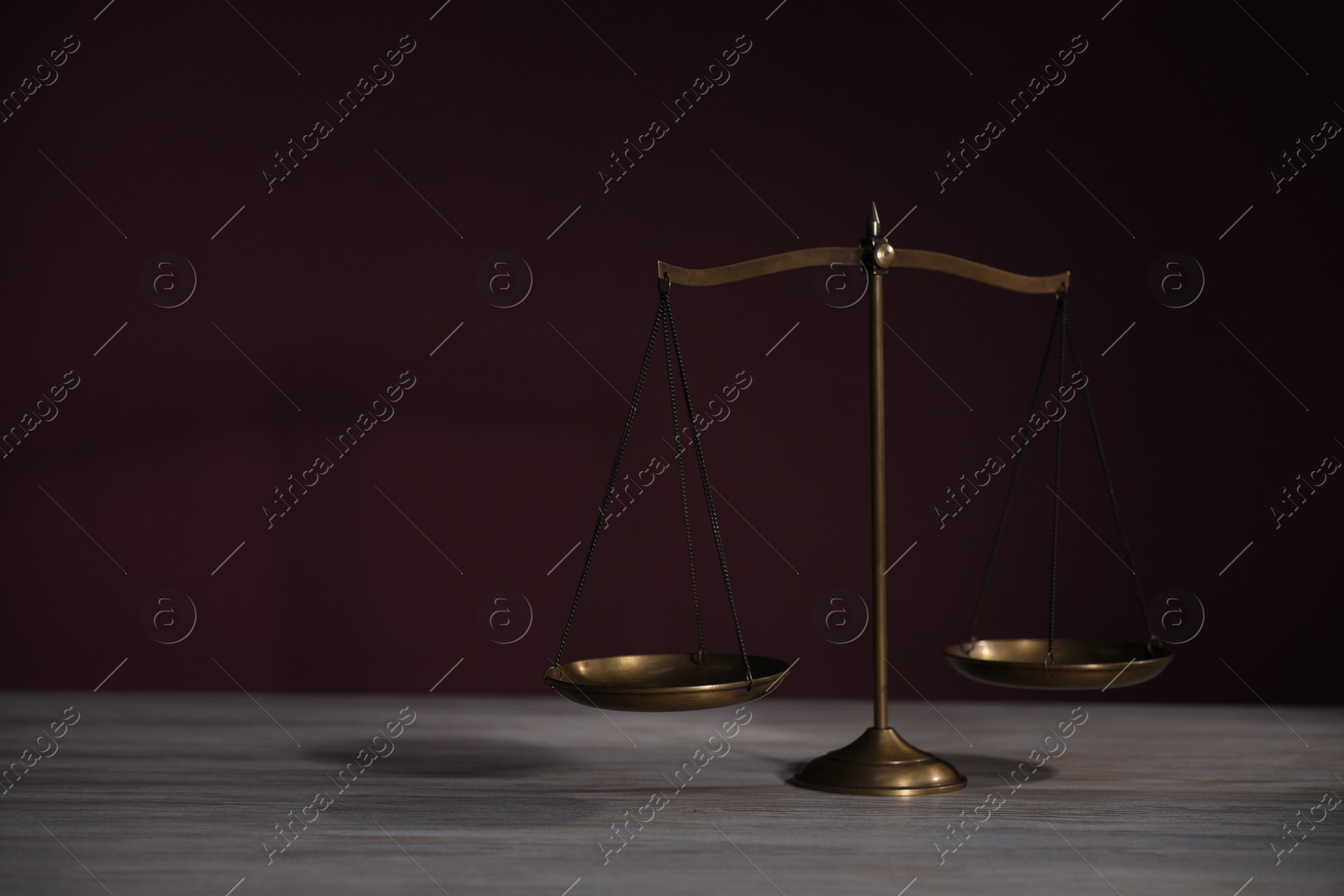 Photo of Scales of justice on wooden table against dark background. Space for text