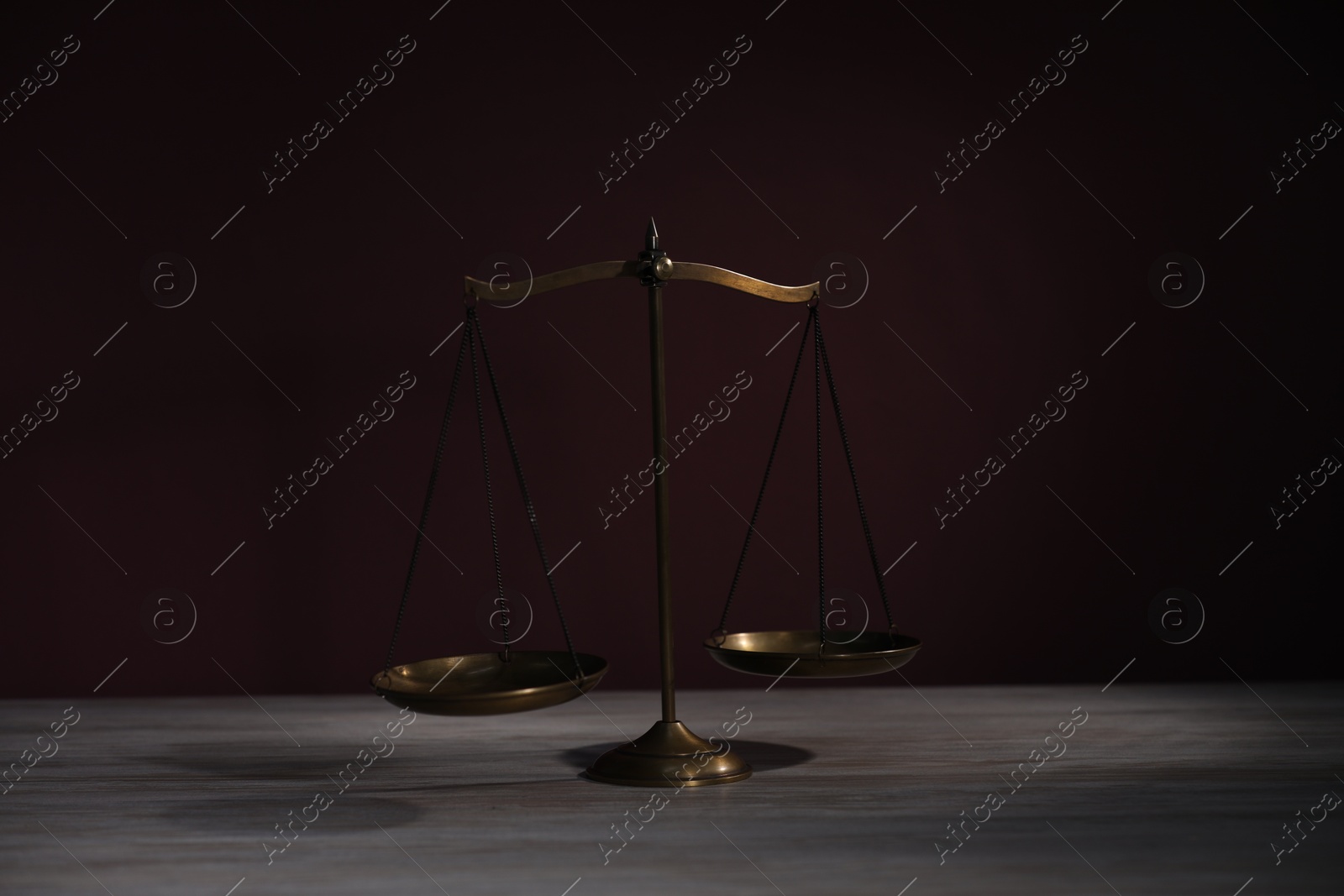 Scales of justice on wooden table against dark background Photo of Scales of justice on wooden table against dark background