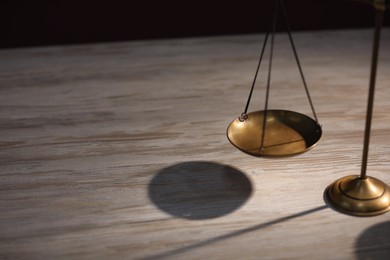 Photo of Scales of justice on wooden table, closeup. Space for text