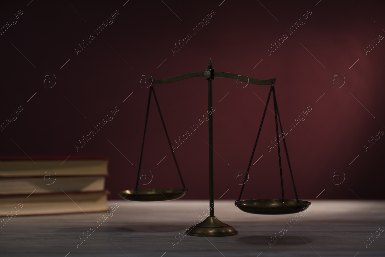 Scales of justice and books on wooden table against dark background, selective focus Photo of Scales of justice and books on wooden table against dark background, selective focus