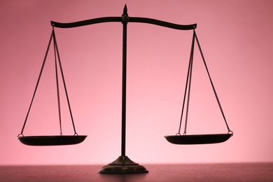 Photo of Scales of justice on table against color background