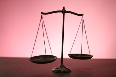 Photo of Scales of justice on table against color background