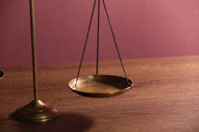 Photo of Scales of justice on wooden table, closeup