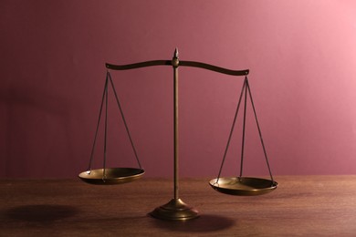 Photo of Scales of justice on table against color background