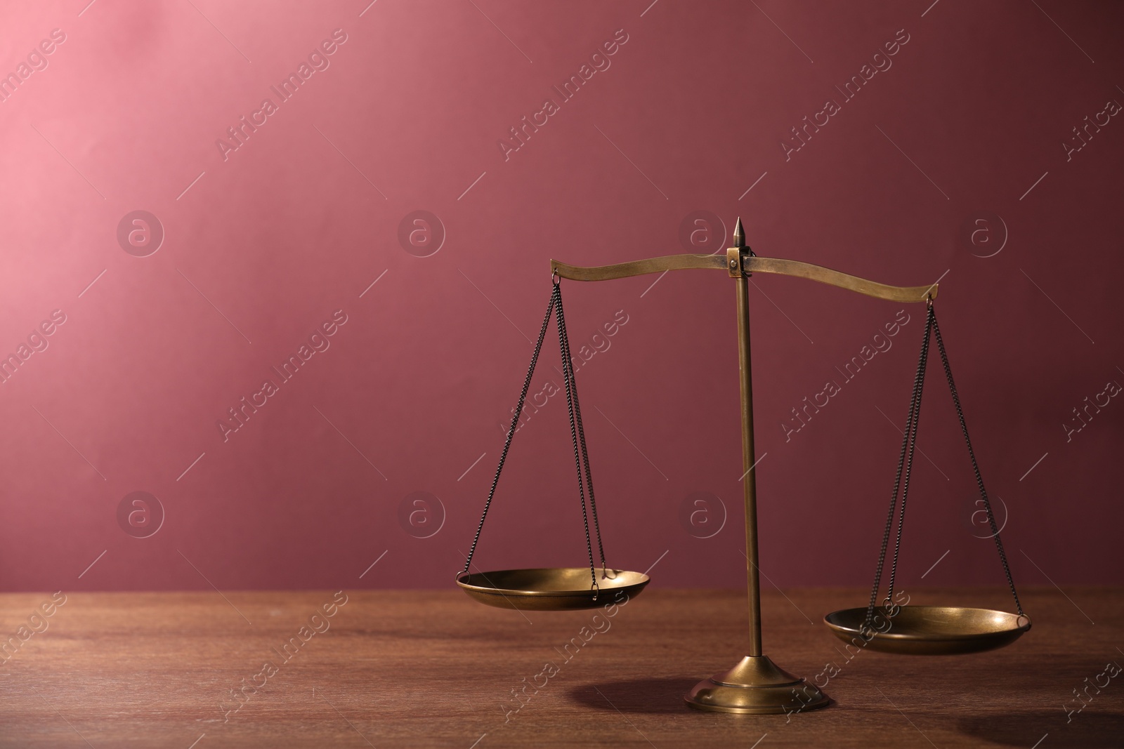 Scales of justice on wooden table against color background. Space for text Photo of Scales of justice on wooden table against color background. Space for text