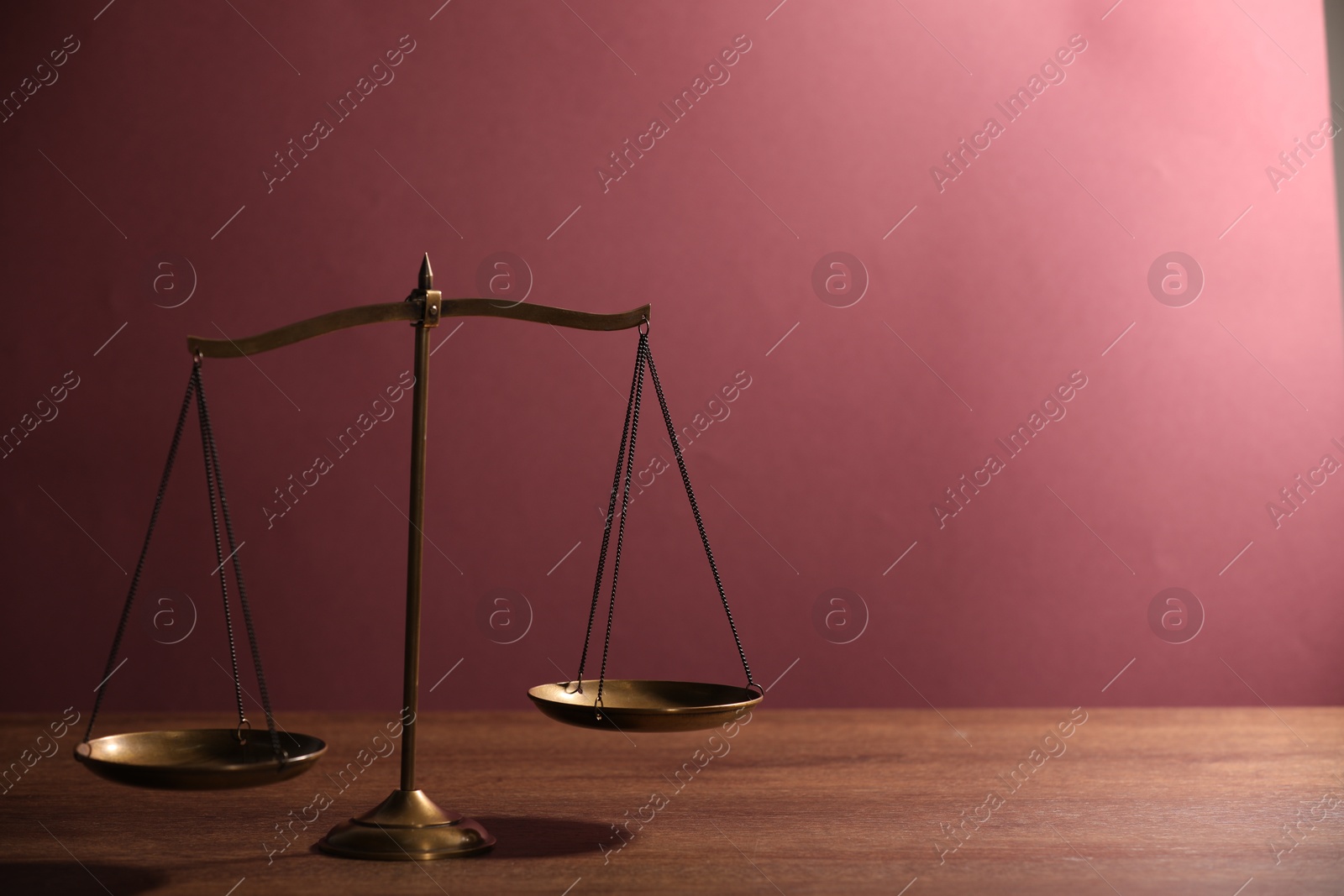 Scales of justice on wooden table against color background. Space for text Photo of Scales of justice on wooden table against color background. Space for text