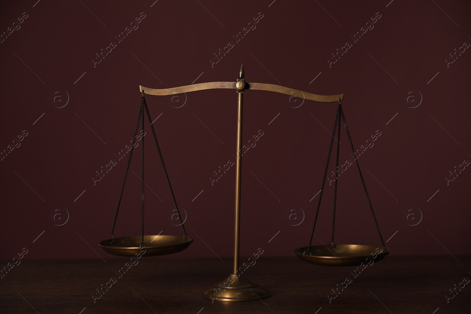 Photo of Scales of justice on wooden table against dark background