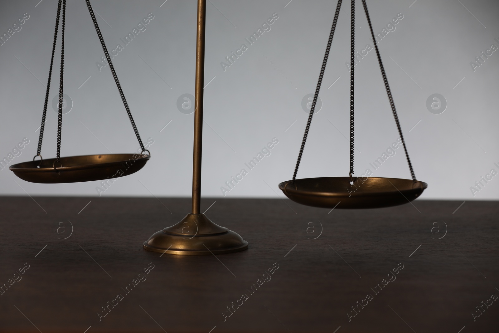 Scales of justice on table against light background, closeup Photo of Scales of justice on table against light background, closeup