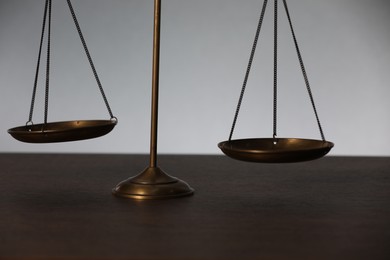 Photo of Scales of justice on table against light background, closeup