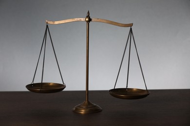 Photo of Scales of justice on table against light background