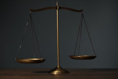 Photo of Scales of justice on table against gray background, closeup