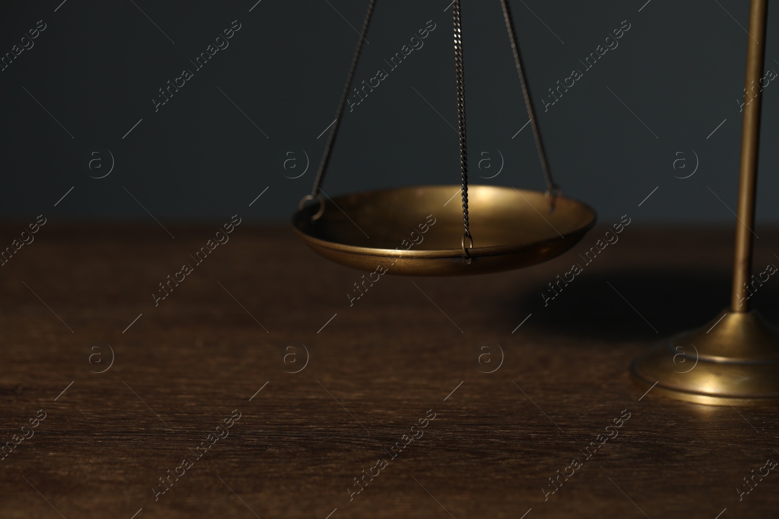 Photo of Scales of justice on wooden table against gray background, closeup. Space for text