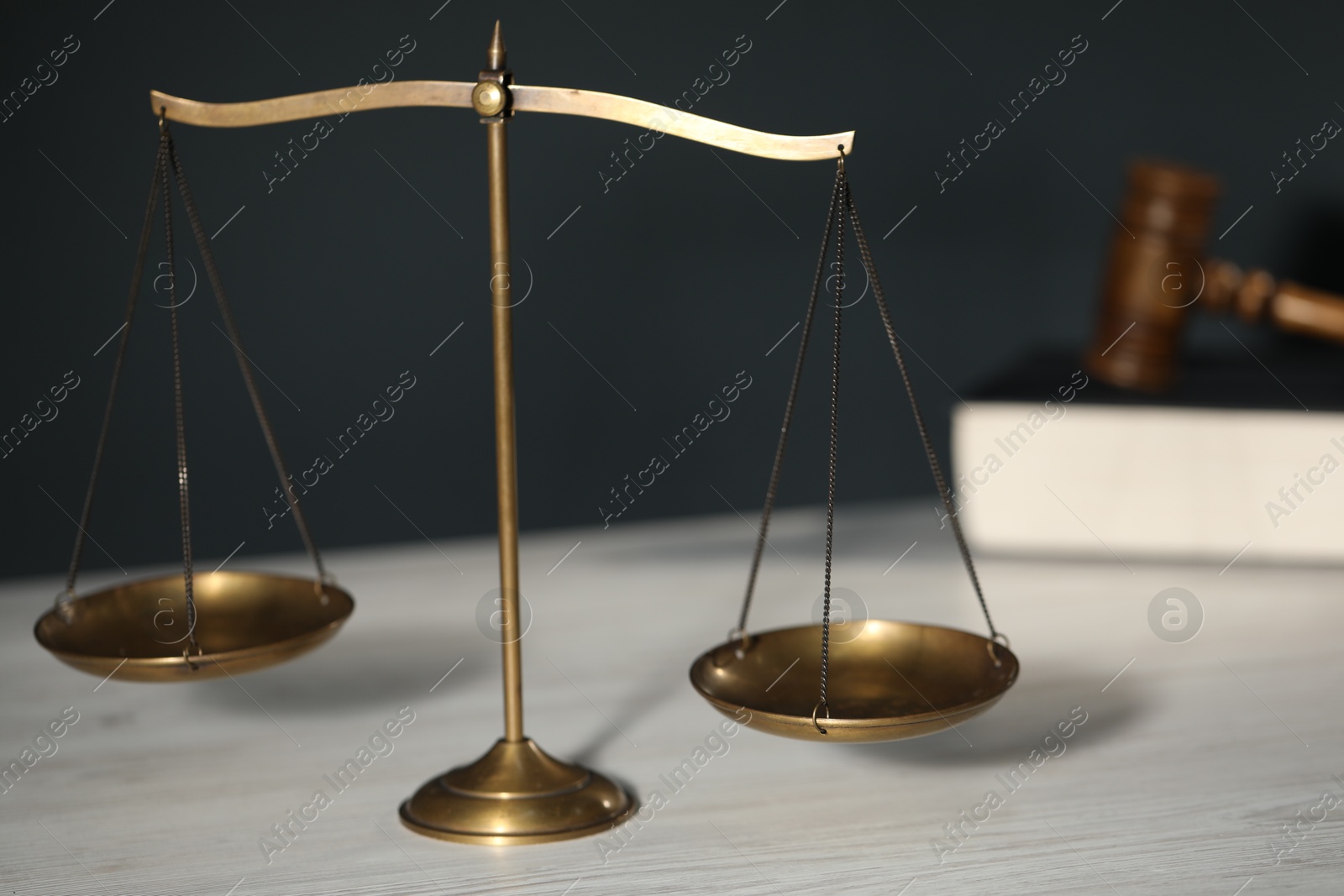 Scales of justice, book and judge's gavel on light wooden table against gray background, closeup Photo of Scales of justice, book and judge's gavel on light wooden table against gray background, closeup