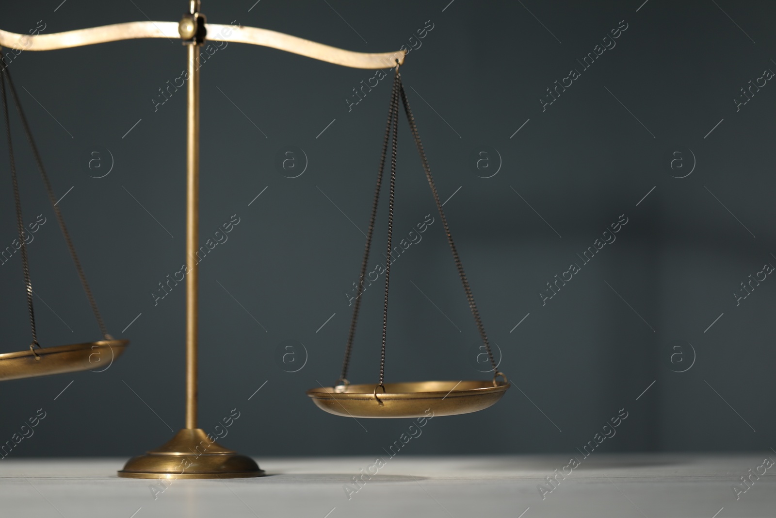 Scales of justice on table against gray background, closeup. Space for text Photo of Scales of justice on table against gray background, closeup. Space for text