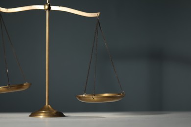 Photo of Scales of justice on table against gray background, closeup. Space for text