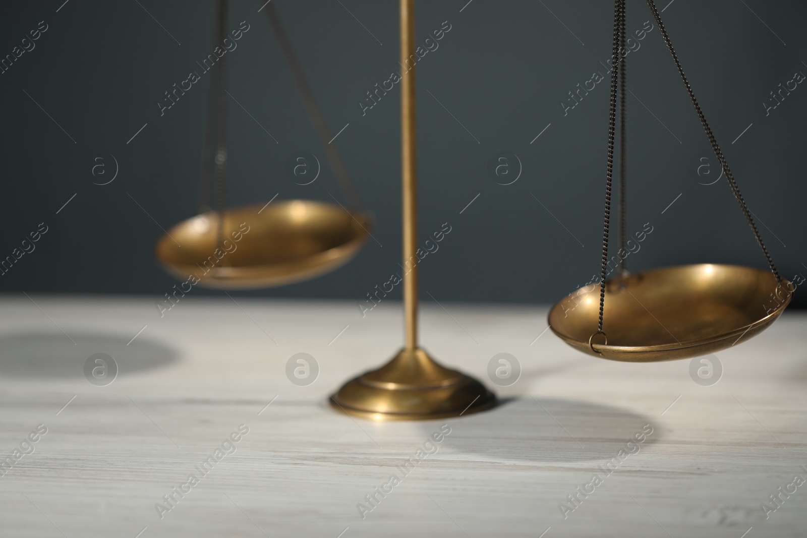 Scales of justice on light wooden table against gray background, closeup Photo of Scales of justice on light wooden table against gray background, closeup