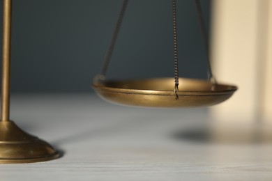 Photo of Scales of justice on table against blurred background, closeup