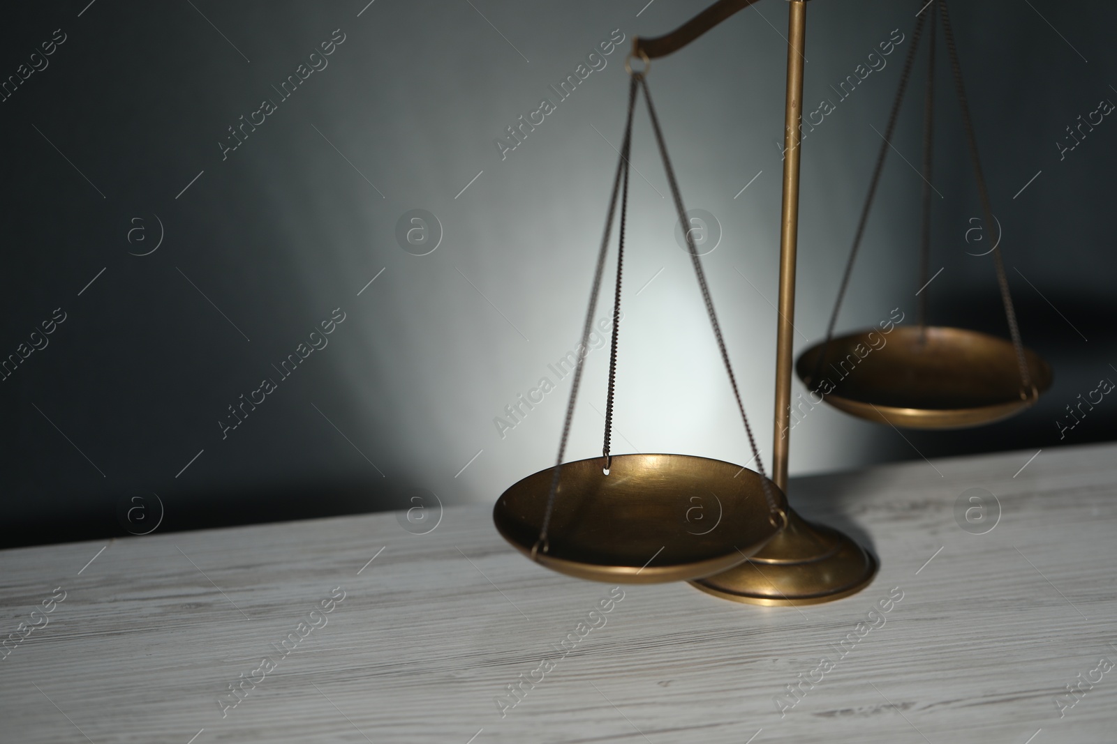 Scales of justice on light wooden table against gray background, closeup. Space for text Photo of Scales of justice on light wooden table against gray background, closeup. Space for text