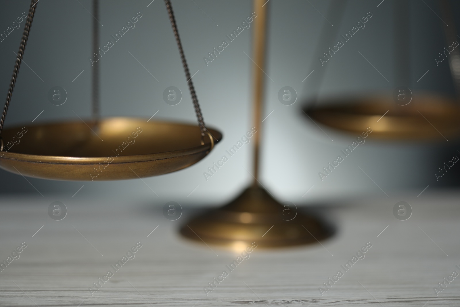 Scales of justice on table against blurred background, closeup Photo of Scales of justice on table against blurred background, closeup