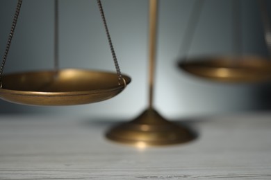 Photo of Scales of justice on table against blurred background, closeup