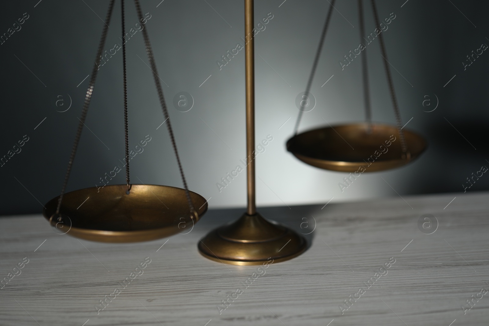 Scales of justice on light wooden table against gray background, closeup Photo of Scales of justice on light wooden table against gray background, closeup