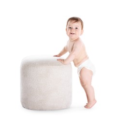 Photo of First steps. Cute little baby in diaper near pouf on white background