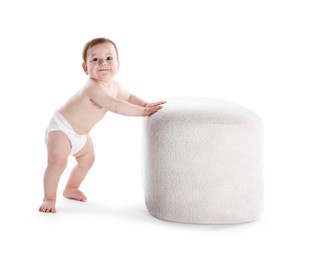 Photo of First steps. Cute little baby in diaper near pouf on white background