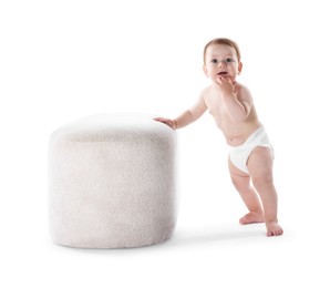 Photo of First steps. Cute little baby in diaper near pouf on white background