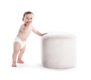 Photo of First steps. Cute little baby in diaper near pouf on white background