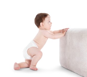 Photo of First steps. Cute little baby in diaper near pouf on white background