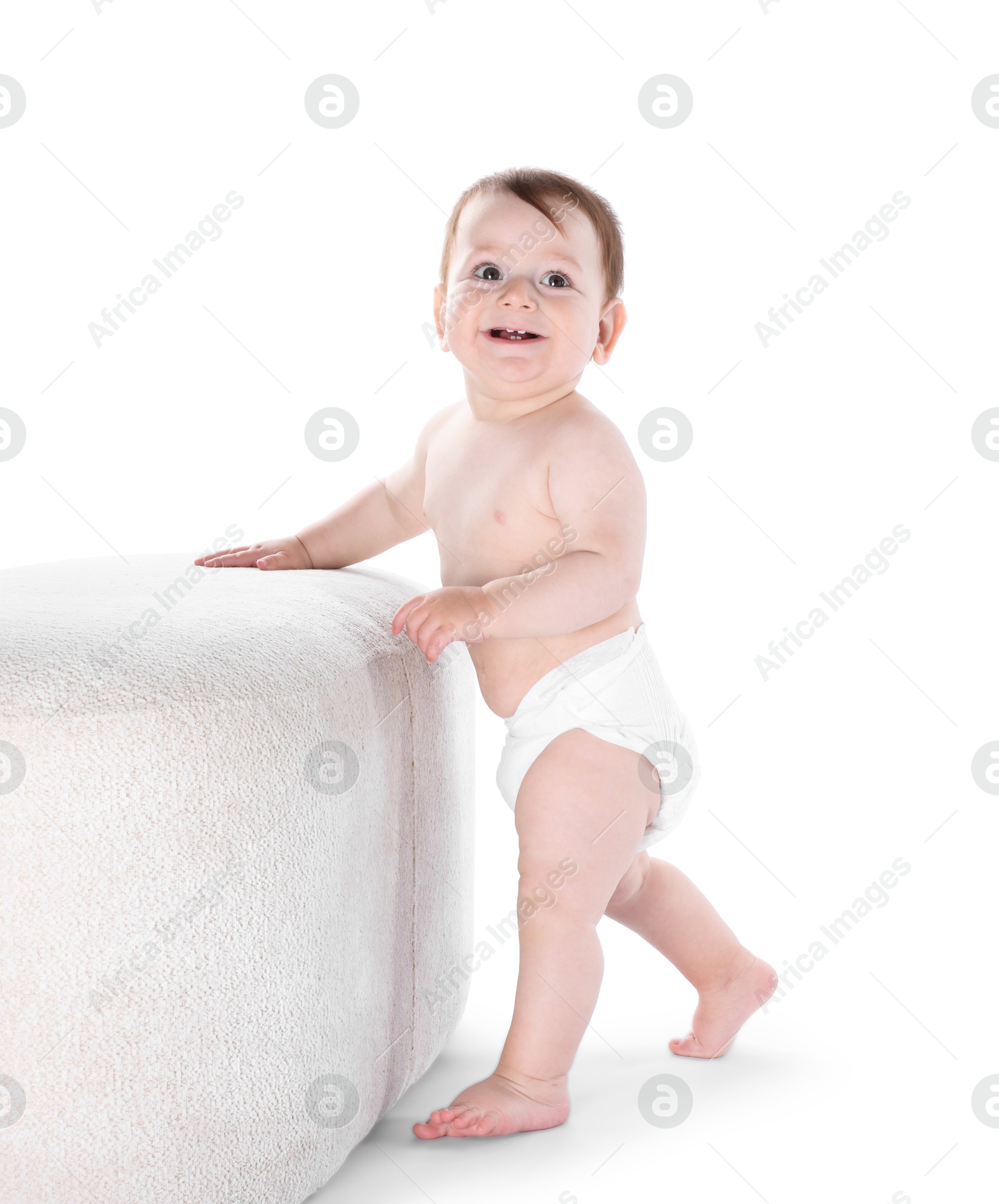 First steps. Cute little baby in diaper near pouf on white background Photo of First steps. Cute little baby in diaper near pouf on white background