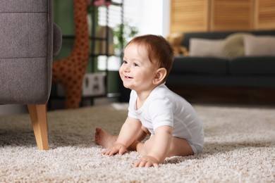 Photo of Cute little baby sitting on carpet at home