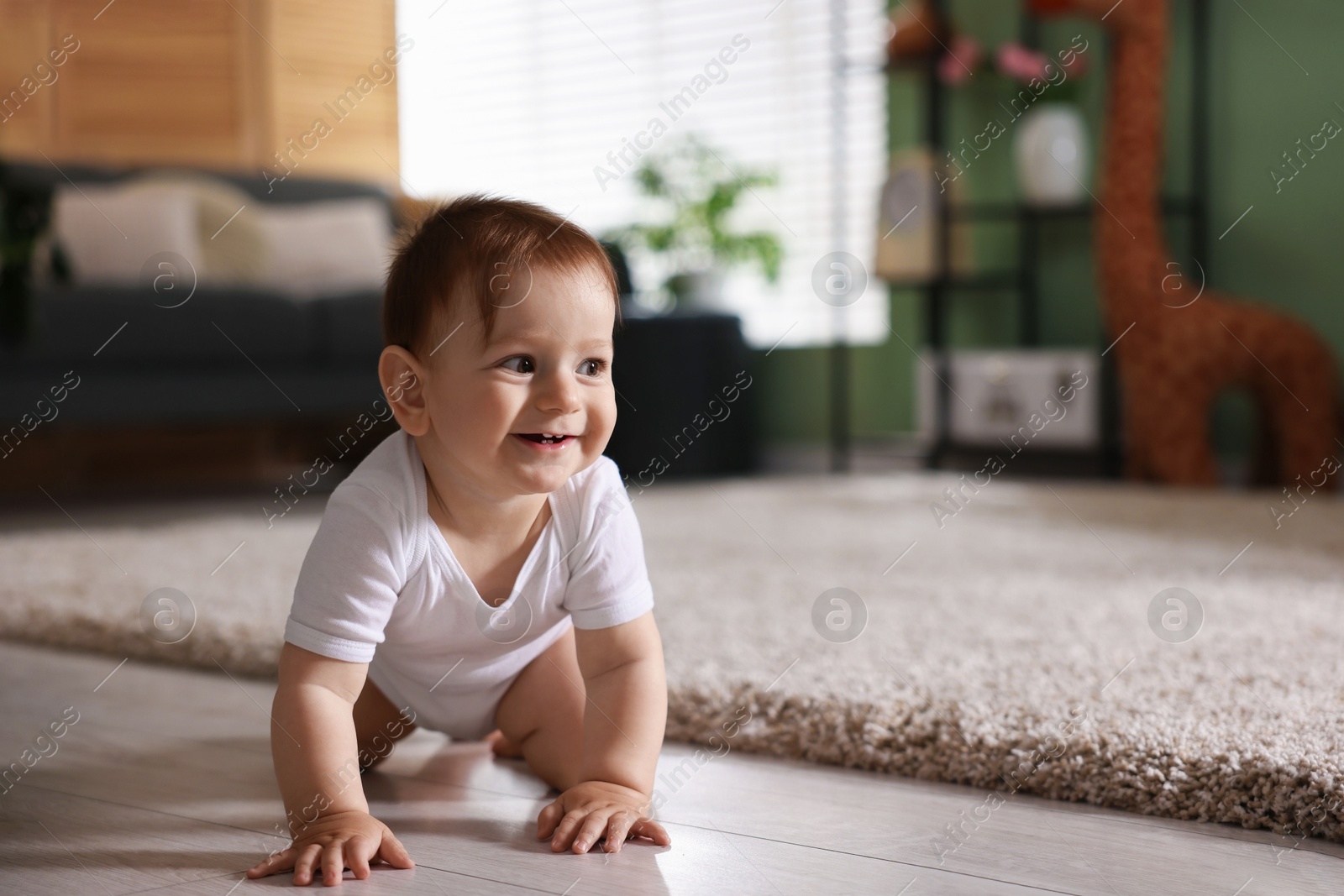 Cute little baby crawling on floor at home, space for text Photo of Cute little baby crawling on floor at home, space for text