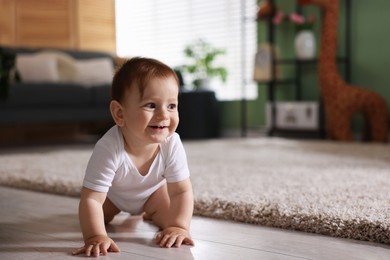 Photo of Cute little baby crawling on floor at home, space for text