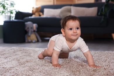 Photo of Cute little baby crawling on carpet at home, space for text