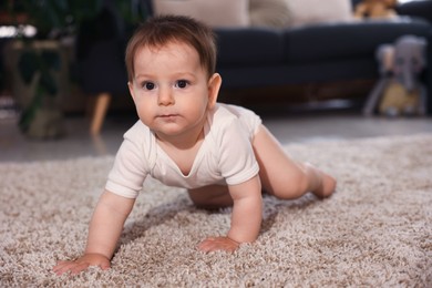 Photo of Cute little baby crawling on carpet at home