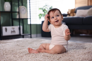 Photo of Cute little baby sitting on carpet at home, space for text